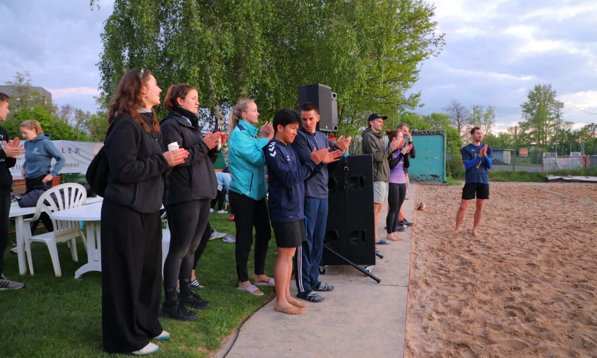 Bild von Leuten die am Rand eines Beachvolleyballfelds stehen und applaudieren